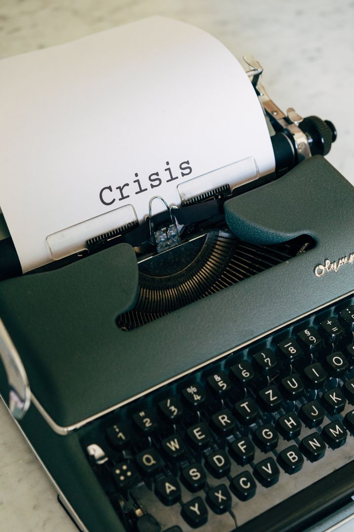 Close-up of a vintage typewriter with the word Crisis typed on paper.